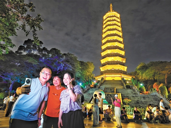 成功登頂?shù)氖忻衲贸鍪謾C與龍光塔合影。