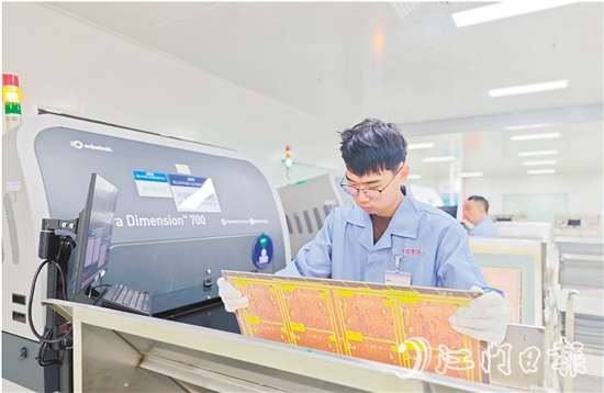 在鶴山中富生產車間，員工操作自動化設備趕制電路板。