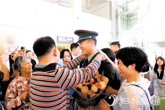 身著軍裝的返鄉(xiāng)退役士兵逐一出站，迎接他們的是鮮花與擁抱。