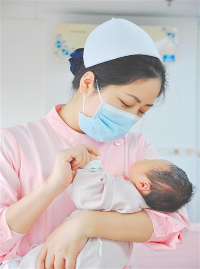 這是一雙托起生命的手。江門市中心醫(yī)院愛嬰?yún)^(qū)主管護(hù)師湯玲玲正在安撫哭鬧的寶寶。她一手環(huán)住襁褓，一手牽起寶寶的小手，動(dòng)作舒緩而溫柔。在這里，生命的啼哭與溫柔的守護(hù)相遇，匯聚成世間至暖的力量。（林錦棠