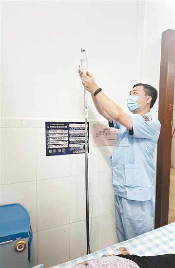 吳益浩核對(duì)藥液、為患者調(diào)整輸液流速。