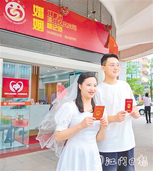 一對新人在蓬江區(qū)民政局婚姻登記處門口合影留念。