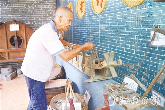 新華村打造農(nóng)耕文化展館，留住鄉(xiāng)村記憶。圖為村中老人向記者介紹農(nóng)具。