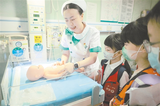 醫(yī)護人員為小記者演示新生兒輻射保暖臺的用途。