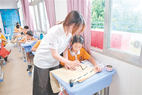 社會實踐隊隊員指導(dǎo)學(xué)生練習(xí)硬筆、軟筆書法。