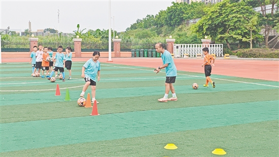 學(xué)生在教練的指導(dǎo)下學(xué)習(xí)足球技巧。