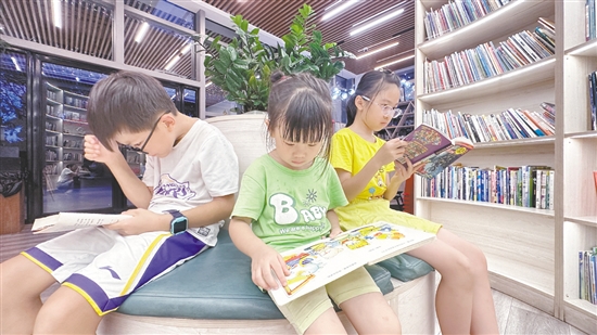 低年級學(xué)生圍坐在書架旁閱讀繪本。