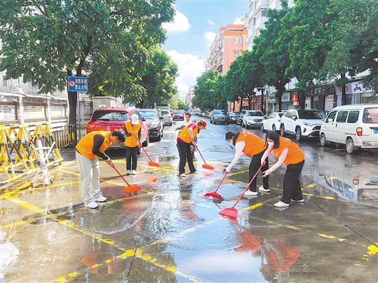 廣東江門中醫(yī)藥職業(yè)學(xué)院大學(xué)生志愿者合力清掃街道積水。