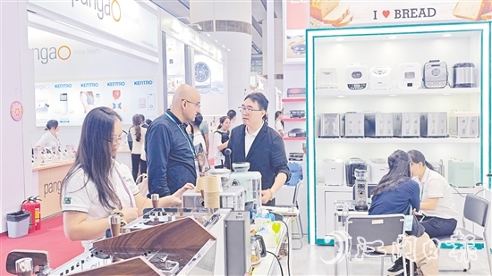 外國客商在一家蓬江區(qū)家電企業(yè)的展區(qū)前洽談合作。任佳燕