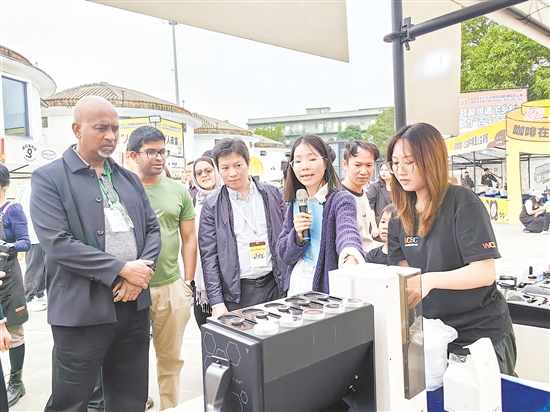 外國(guó)友人被活動(dòng)現(xiàn)場(chǎng)的智能拼豆機(jī)所吸引，點(diǎn)贊僑鄉(xiāng)江門創(chuàng)新活力。